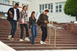 Going down the stairs. Four young students in casual clothes are together outdoors