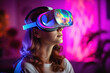 Portrait of young pretty woman at home, wearing VR goggles, immersed in a virtual reality, playing interactive games under pink neon lights, experiencing the future of entertainment.
