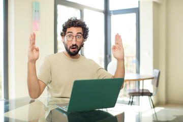 Wall Mural - young adult bearded man with a laptop holding an object with both hands, showing, offering or advertising an object