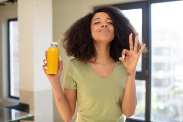 Wall Mural - pretty afro black woman feeling happy, showing approval with okay gesture. orange juice concept