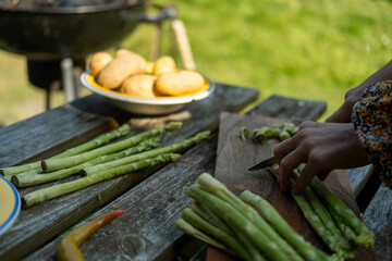 Wall Mural - Women's hands cutting asparagus. Preparing for green grilling. Vegan meals.