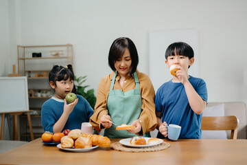 ￼￼￼Asian family making food in kitchen at home. Portrait of smiling mother, dad and children standing with dough bake cookie and cake ingredientat cooking counter