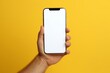 © rzrstudio - Mockup image of a person holding mobile phone with blank desktop screen isolated on yellow background