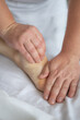 © Tatsiana - Close-up of man doing foot massage on white background. Reflexology foot massage. Tired feet concept. Vertical
