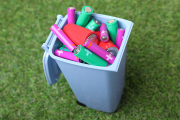 Sticker - Many used batteries in recycling bin on green grass