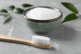 Fototapeta Sypialnia - Bamboo toothbrush and bowl of baking soda on light gray marble table, closeup