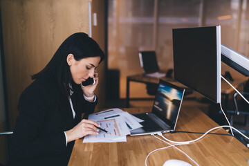 Wall Mural - Focused woman working and talking on smartphone