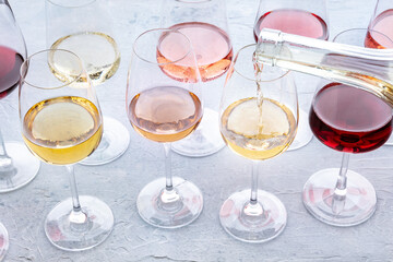 Wine pour into a glass at a tasting. Rose, red, and white wine, drinks on a table at a winery. An assortment of wines of many different colors