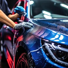 An Employee Of A Car Wash Or Car Shop Thoroughly Washes A Blue Car.