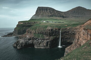 Sticker - Majestic waterfall cascading down a rocky cliff face in Gasadalur, Faroe Islands