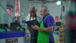 © Marco - Senior Supermarket Employees with Tablet Device, Teamwork Scene of Older Manager Instructing Colleague