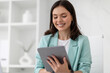 © Prostock-studio - Happy pretty young caucasian businesswoman in suit chatting on tablet in office interior