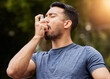 © Ilzer/peopleimages.com - Man, breathe or asthma pump outdoor in park for help with health risk, cough treatment and air for exercise. Asian male runner, spray and medicine inhaler in nature for lungs, oxygen and wellness