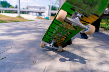 Close-up of a young boy doing a skateboarding trick on the path of a city park against the background of trees