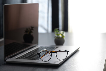 Wall Mural - laptop and glasses on the desktop on a blurred background.