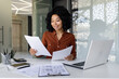 © Liubomir - Young successful financier works with documents and contracts inside the office, satisfied with the results of financial activities, businesswoman reviews accounts, reports and contracts, laptop.