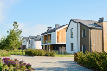 Wall Mural - Perspective view of modern two storey village houses with small front yards surrounded by fence and green vegetation