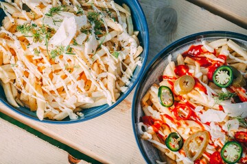 Two bowls of french fries topped with sauce