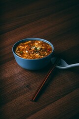 Wall Mural - a bowl of stew sits on a table with a spoon