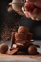 Poster - Hand sprinkles cocoa powder on chocolate candies.