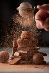 Wall Mural - Hand sprinkles cocoa powder on chocolate candies.