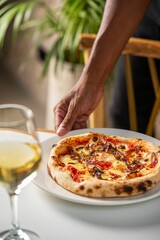 Wall Mural - a hand grabbing up the topping on a pizza and glass of wine