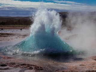 Wall Mural - Majestic geyser erupting on the side of Iceland against a blue sky