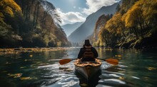 A Man Is Kayaking On A Lake Among The Mountains.