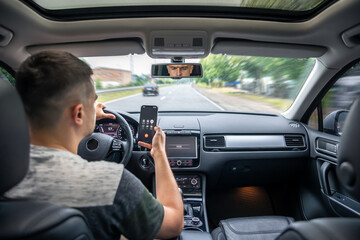 Wall Mural - Businessman talking on cell phone while driving.