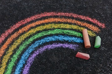 Close-up of a rainbow painted on a road with sidewalk chalk, shot from above