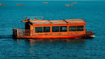 Canvas Print - Single red boat is seen drifting in a tranquil body of water