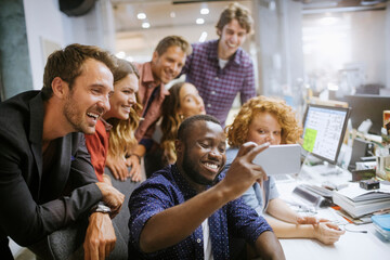 young group of people taking a selfie while working in the office together
