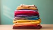© ckybe - Stack of colorful clothes. Pile of clothing on table empty space background. Laundry and household.