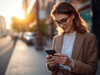 © Islam - Close-up image of business woman watching smart mobile phone device outdoors. Businesswoman networking typing an sms message in city street.