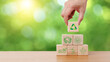 © TimmyTimTim - Hand holding wooden cube block with recycle, earth, eco friendly and green energy icon in green background. Sustainable and environmental responsibility concept.