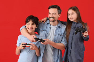 Wall Mural - Little children with their father playing video game on red background