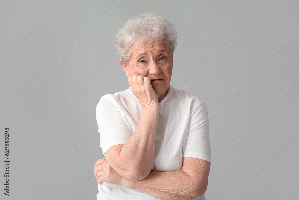 Upset senior woman on grey background