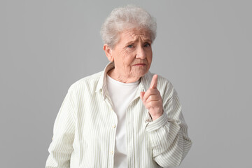 Poster - Upset senior woman with raised index finger on grey background