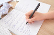 © Pixel-Shot - Woman writing math formulas in copybook on wooden table