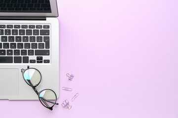 Poster - Modern laptop, paper clips and eyeglasses on pink background