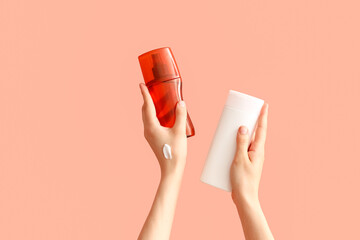 Wall Mural - Female hands with bottles of sunscreen cream on color background