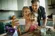 © Geber86 - Young family taking a selfie while baking in the kitchen