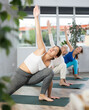 Three sport women doing yoga in group workouts practice the Utthita Parshvakonasana pose in a fitness studio