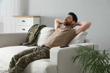 Wall Mural - Soldier napping on soft sofa in living room. Military service