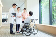 © taka - 車椅子に乗った男性の患者と会話をする医師