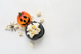 Fototapeta Sawanna - Bowl with tasty popcorn, pumpkin and spider on white background. Halloween celebration