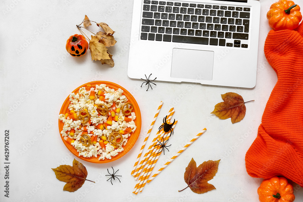 Composition with tasty popcorn, laptop and sweater on white background. Halloween celebration