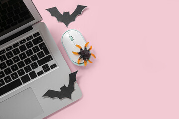 Modern laptop, mouse, tasty candy and paper bats for Halloween on pink background, closeup