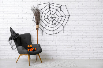 Wall Mural - Armchair with gift boxes, broom, hat and web hanging on light brick wall in room