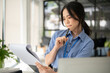 A focused and smart Asian businesswoman is reading and examining business documents